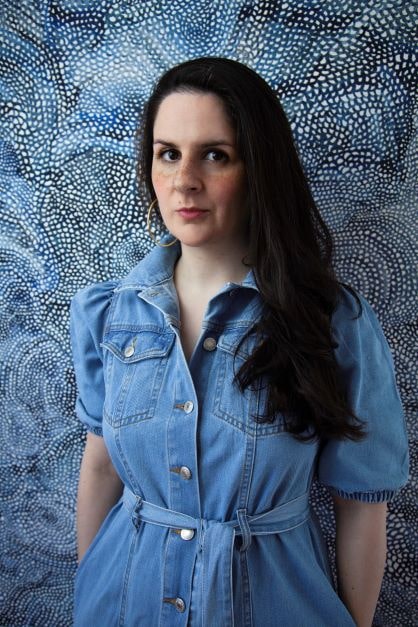 A photograph of Karina Lickorish Quinn, a women with long dark hair, wearing a blue dress.